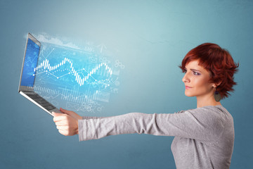 Woman holding laptop projecting financial information, diagrams and charts 
