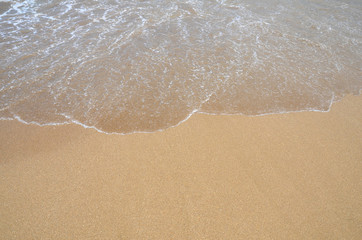 Clear wave covering sandy beach