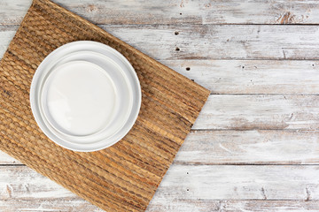 empty white dishes (plate, bowl) on a white wooden background (table), top view, copy space, mock-up