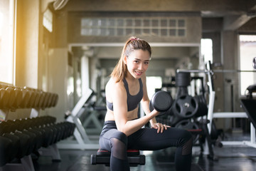 Fototapeta na wymiar Sporty asian beautiful woman exercise with dumbbells,Female in sportswear does the exercises at gym