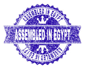 ASSEMBLED IN EGYPT rosette stamp watermark with grunge texture. Designed with round rosette, ribbon and small crowns. Blue vector rubber print of ASSEMBLED IN EGYPT label with grunge style.