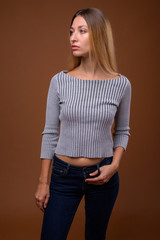 Studio shot of young beautiful woman thinking against brown background