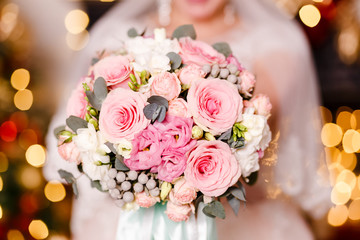 a delicate bouquet of white and pink roses in the hands of the bride