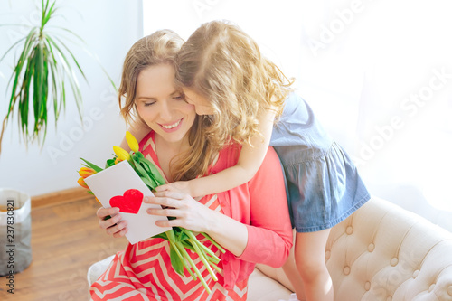 Happy family daughter congratulates her mother on the holiday gives a card and flowers tulips. Happy Mother's Day. international women day. Selective focus.