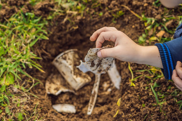 The boy plays recycling. He buries plastic disposable dishes and biodegradable dishes. ...