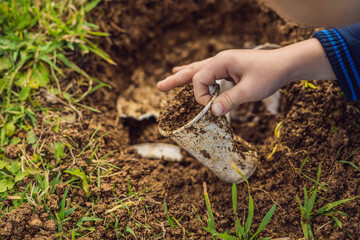 The boy plays recycling. He buries plastic disposable dishes and biodegradable dishes.  biodegradable dishes began to decompose and plastic did not
