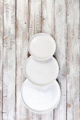 Snowman of plates on a wooden background, top view