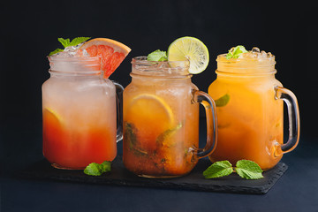 A variety of citrus cocktails vintage glass mason jars with mint and grapefruit. Dark background with copy space for a menu.