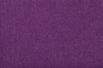 Dark purple matt suede fabric closeup. Velvet texture of felt.