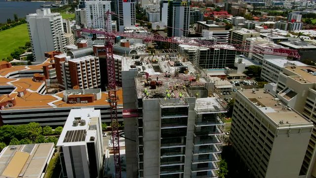 Aerial shot of a busy construction site in Perth CBD with workers and a crane operator working hard on a high-rise building in East Perth, Western Australia.