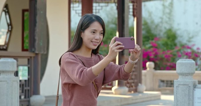 Woman take photo on cellphone in chinese garden