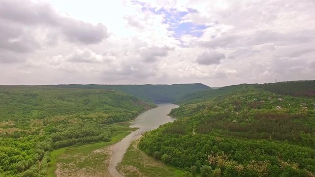 Amazing aerial view of river valley with small settlement in the forest