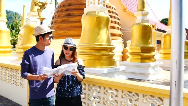 Travel Video A couple of blogger tourists from Southeast Asia is using the map to find the path of the attraction. Landmark in the old City of Phuket during write travel reviews or vacation in travel.