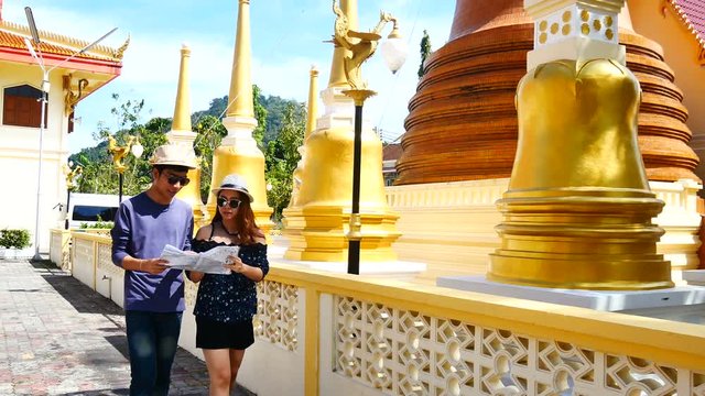 Travel Video A couple of blogger tourists from Southeast Asia is using the map to find the path of the attraction. Landmark in the old City of Phuket during write travel reviews or vacation in travel.