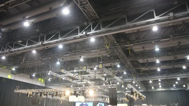 unfocused concert hall. audience people sitting conference concert hall seats dark night light rays inside exhibition fair blurred mooving camera meeting business.