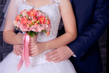 newlyweds. the husband gently embraces the wife. the bride holds the wedding bouquet in hand. bright bridal bouquet