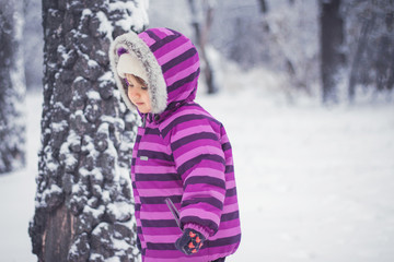 portrait of a little girl in a purple suit playing in the snow