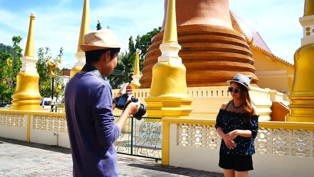 A tourists blogger from Southeast Asia is taking a photo to a co-worker trip in Phuket Old Town to write a tourist review. During vacation in travel.