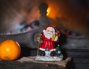 Christmas still life in fireplace. Christmas tree, tangerine, Santa Claus