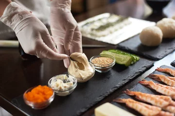 Foto op Canvas Close-up of chef hands preparing japanese food. Japanese chef making sushi rolls at restaurant. © anatoliy_gleb