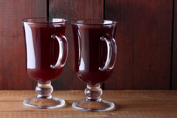 Mulled wine on wooden boards. Christmas mulled wine in glass cups. Alcoholic drink of wine and fruit and honey. Festive drink on wooden boards