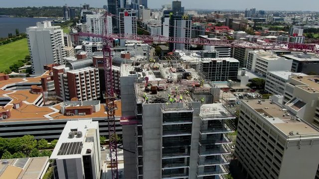 SLOW MOTION Aerial shot of a busy construction site in Perth CBD with workers and a crane operator working hard on a high-rise building in East Perth, Western Australia. 50FPS