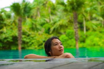 young attractive and beautiful Asian Chinese woman relaxing happy at tropical beach resort swimming at jungle infinity pool enjoying Summer holidays in paradise island