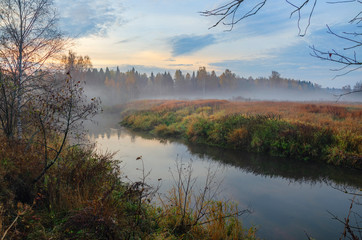 Fototapeta na wymiar Foggy autumn landscape with small forest river. 