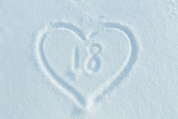 A figure of eighteen written in the snow in the painted heart. Snow texture.