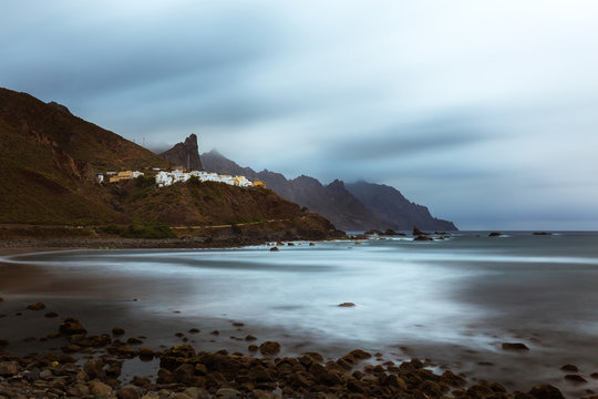 Almaciga village on rocky coastline during stormy weather, landscape with long exposure.