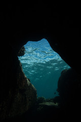 Photo taken while freediving into an underwater cave and looking up towards the brilliant sunlight filtering down through the blue Hawaiian water