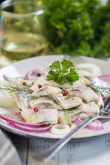 Herring pickle with onion, oil, pepper and dill on plate.