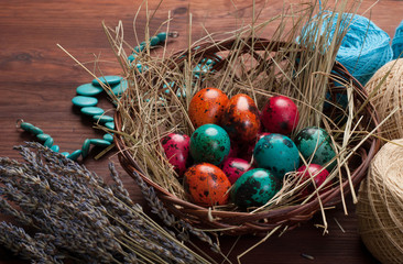 Easter background. Multicolored eggs in a basket, flowers, tangles of thread and decoration on a brown wooden background. Space for text (free space)