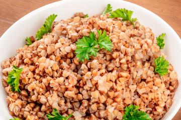 A closeup photo of boiled buckwheat in a bowl, garnished with fresh parsley