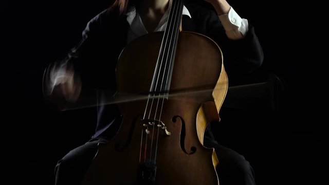 Cellist playing a musical composition .Black background
