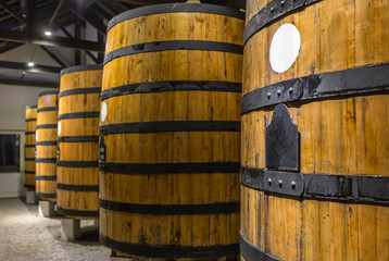 Row of wooden porto wine barrels in wine cellar Porto, Portugal.