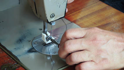 Focus on the old woman's hand is sewing.