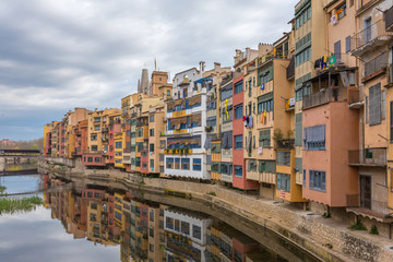 Colorful yellow, red and orange houses with the Catalan flags reflected in water river Onyar, in Girona, Catalonia, Spain.