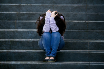depressed student woman or bullied teenager girl sitting outdoors on street staircase scared and...