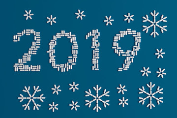 Fototapeta na wymiar Background of a variety of tablets scattered on a blue background in the form of a silhouette figures 2019 and snowflakes 3d illustration