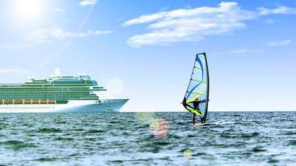 Windsurfer in the sea with a cruise ship on backgroung. Toned, lens sun flare, sun on blue sky....