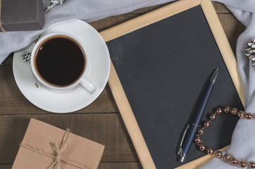 A cup of black coffee in Christmas decor and a slate with free space for text top view