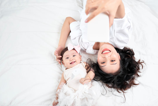 Woman with a baby doing a selfie lying on wooden floor