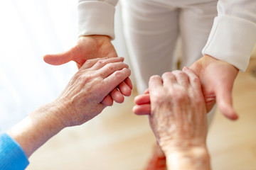 alte Frau wird von einer Pflegerin an den Händen gehalten
