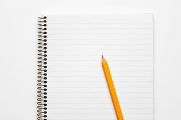 Yellow pencil on a lined notepad on a spiral on a white background