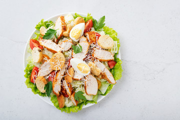 Caesar salad with chicken breast on gray background