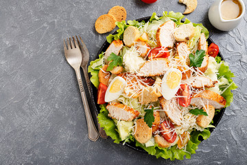 Caesar salad with chicken breast on gray background