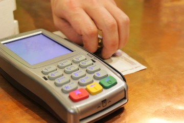credit card machine and a man's hand puts cash