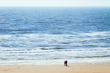 Couple at the beach watching the waves and the panoramic view of the sea