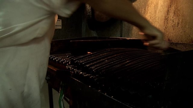 Man Cleaning The Grill And Getting Ready To Prepare Argentine Barbecue.